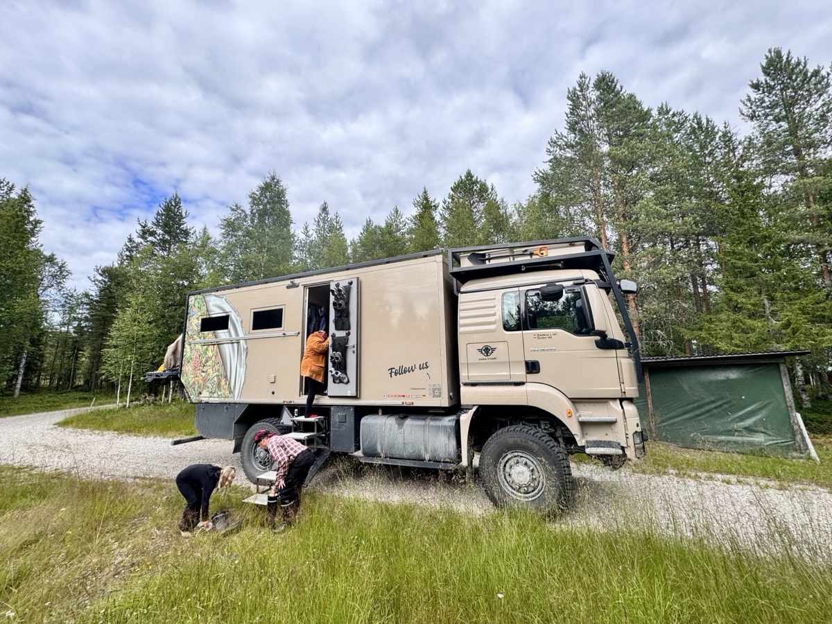 Mammothon steht mit offener Tür am Waldrand, Besucher schauen sich den Truck an