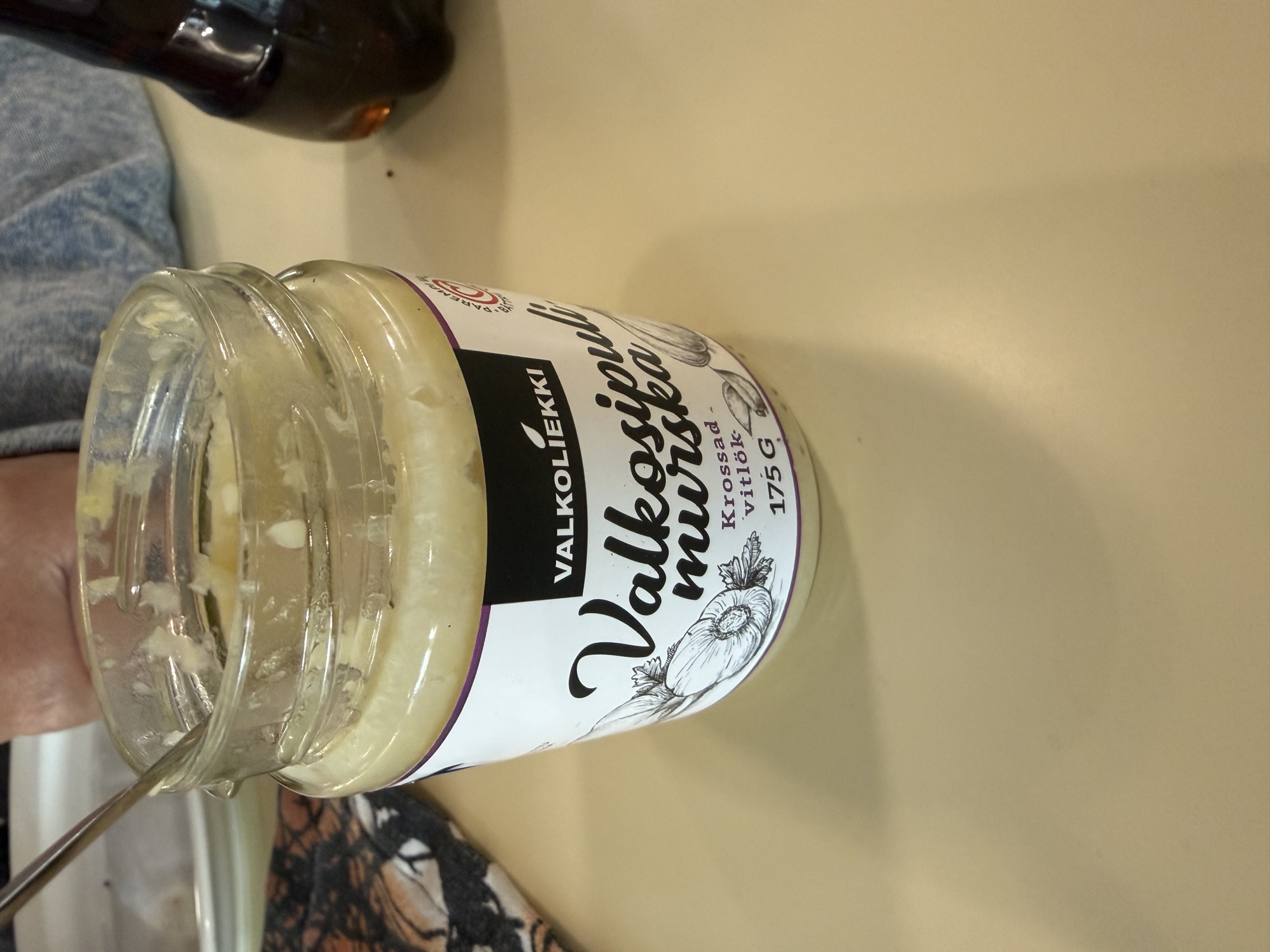 Geöffnetes Glas mit gepresstem Knoblauch und Löffel darin, Etikett mit der Aufschrift Valkosipulimurska