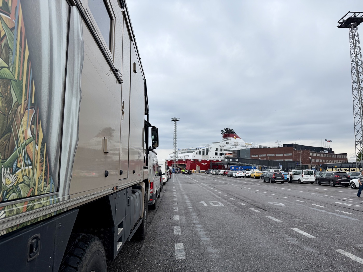 Mammothon steht in der Warteschlange am Fährhafen, hinten ein großes Fährschiff