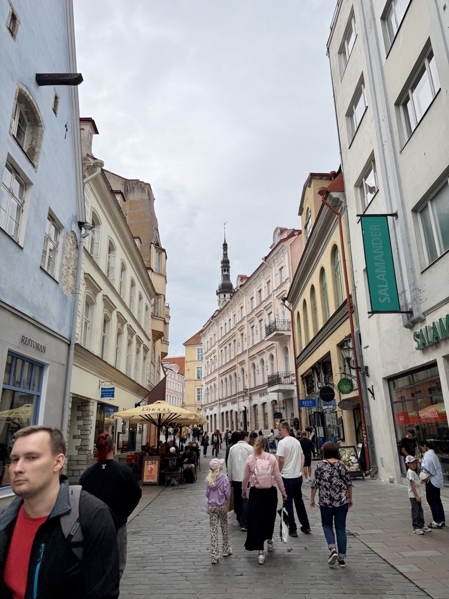 Enge Gasse mit bunten Häusern in der Tallinner Altstadt, im Hintergrund ein Kirchturm