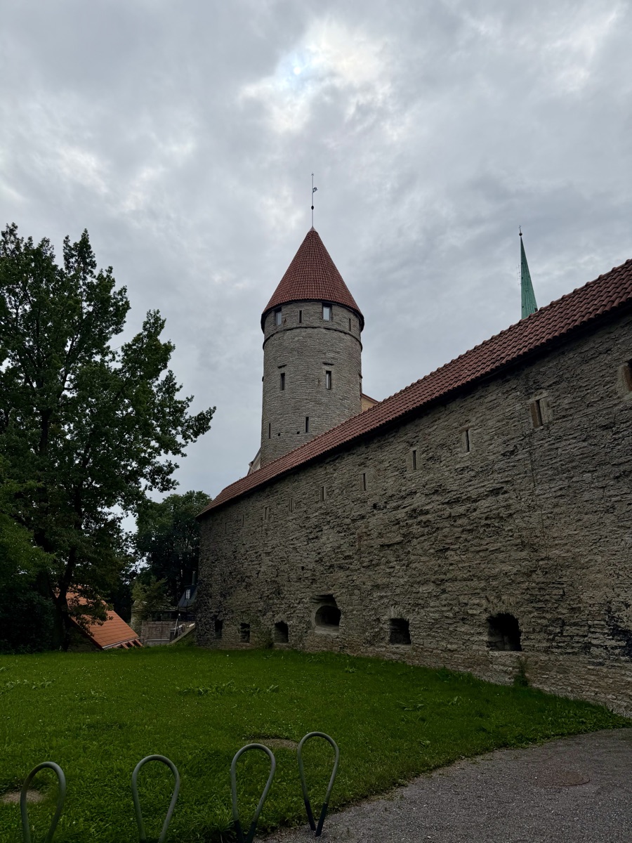 Mächtige Stadtmauer aus Kalkstein mit rundem Turm und rotem Kegeldach
