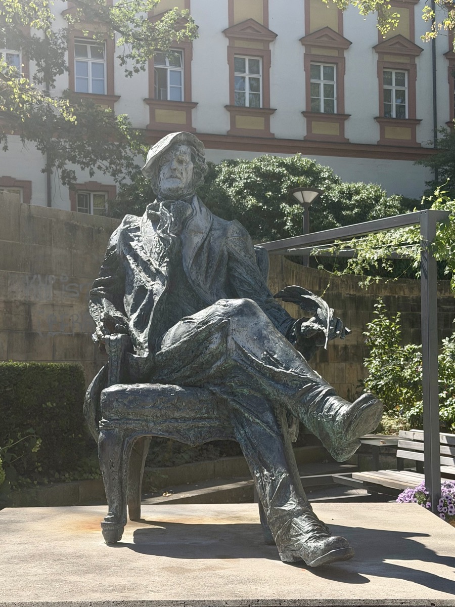 Bronzestatue von Richard Wagner, der mit übergeschlagenen Beinen auf einem Stuhl sitzt