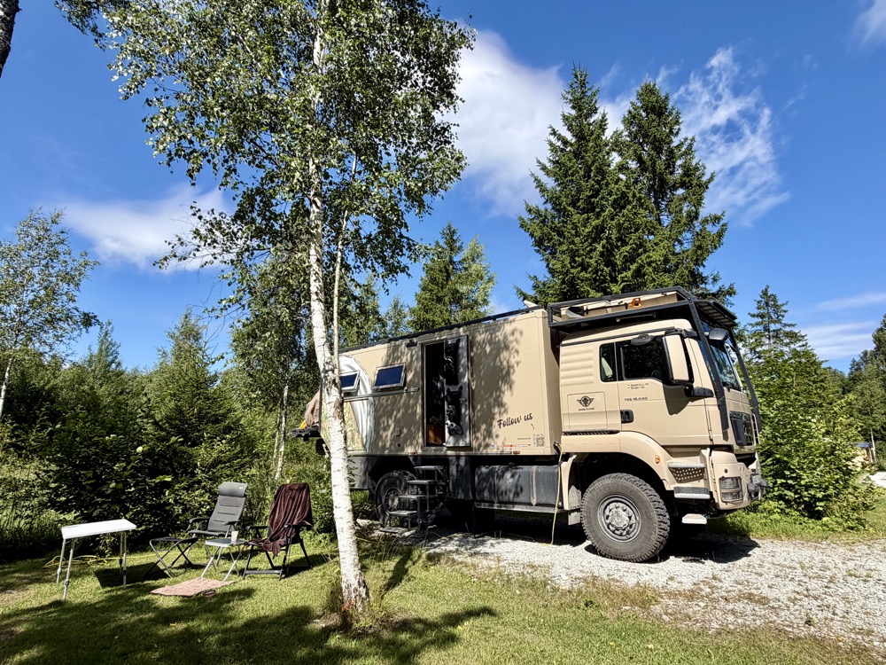 Mammothon steht auf einer Wiese zwischen Birken und Fichten, davor Campingstühle