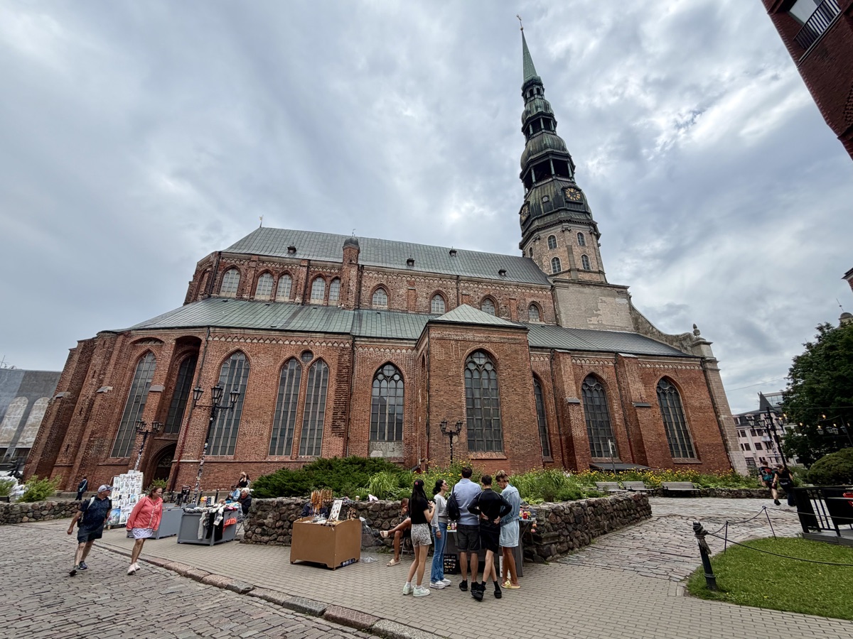 Große Backsteinkirche mit hohem Turm, davor einige Touristen