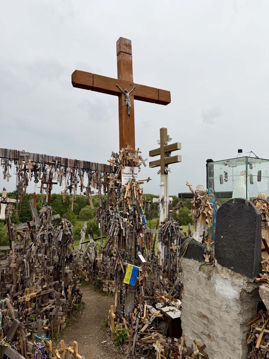 Ein Holzkreuz mit blau-gelber ukrainischer Flagge zwischen unzähligen kleinen Kreuzen