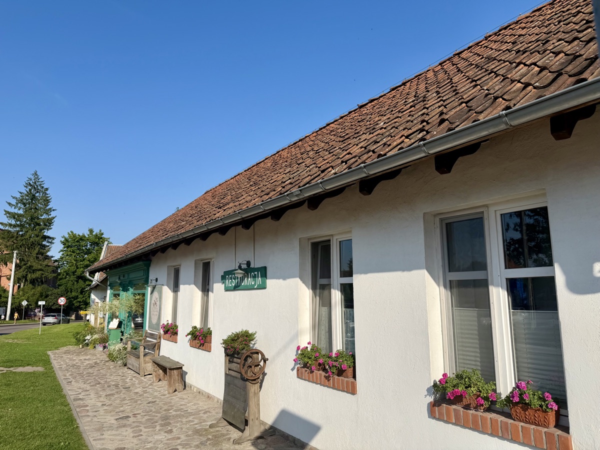 Weißes Landhaus mit rotem Ziegeldach und Blumenkästen an den Fenstern