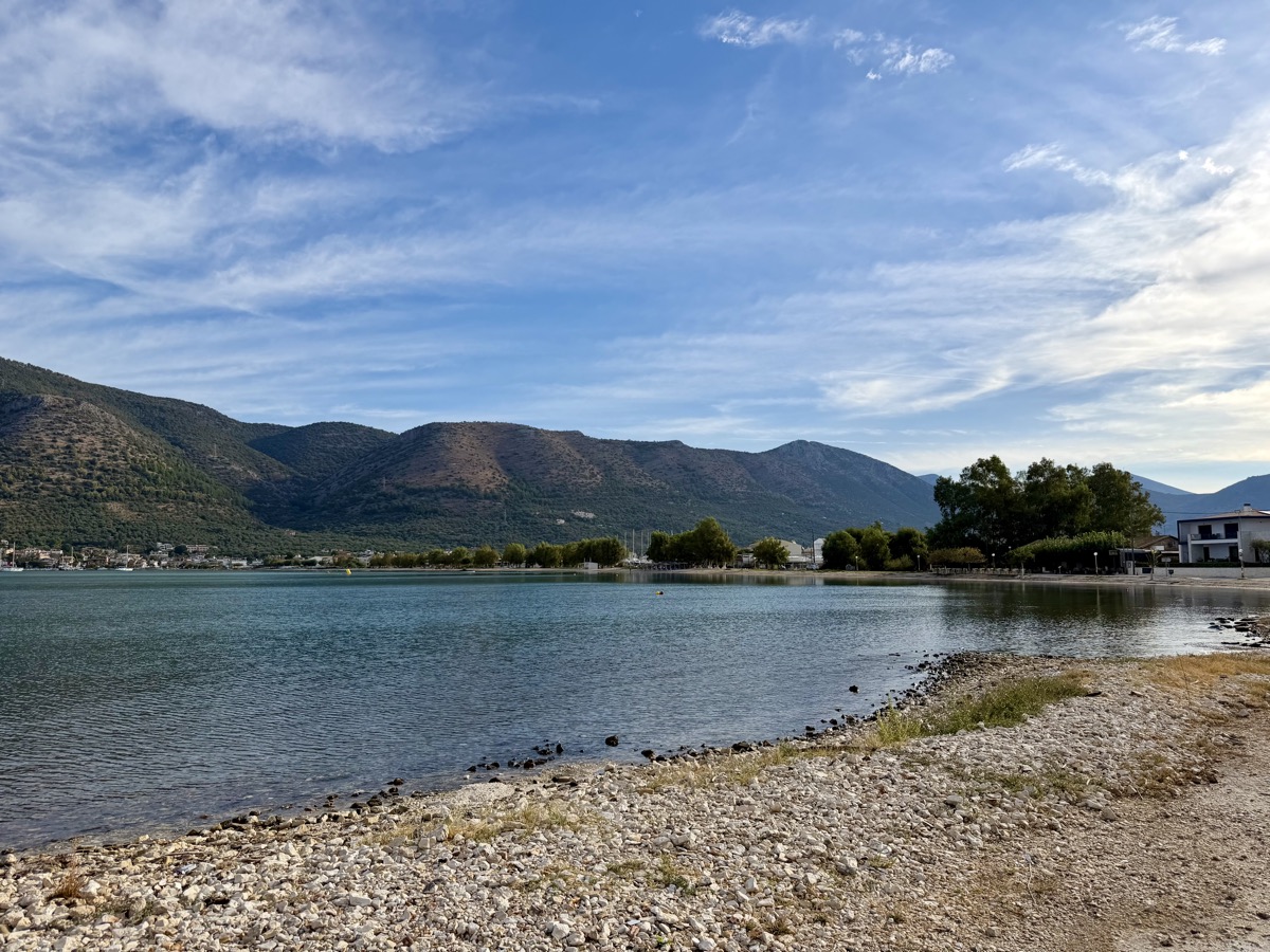 Ruhige Bucht mit Kieselstrand und Bergen im Hintergrund am Morgen