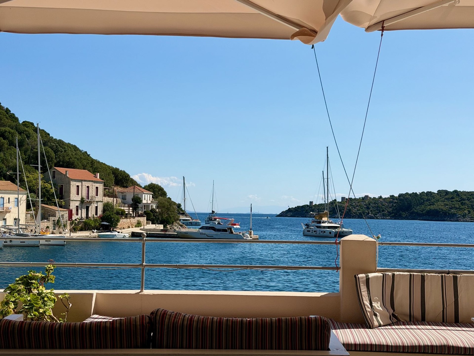 Blick von einer Terrasse über den Hafen von Frikes auf Boote und Häuser