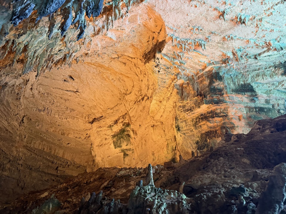 Orange und türkis schimmernde Felswand im Inneren der Höhle