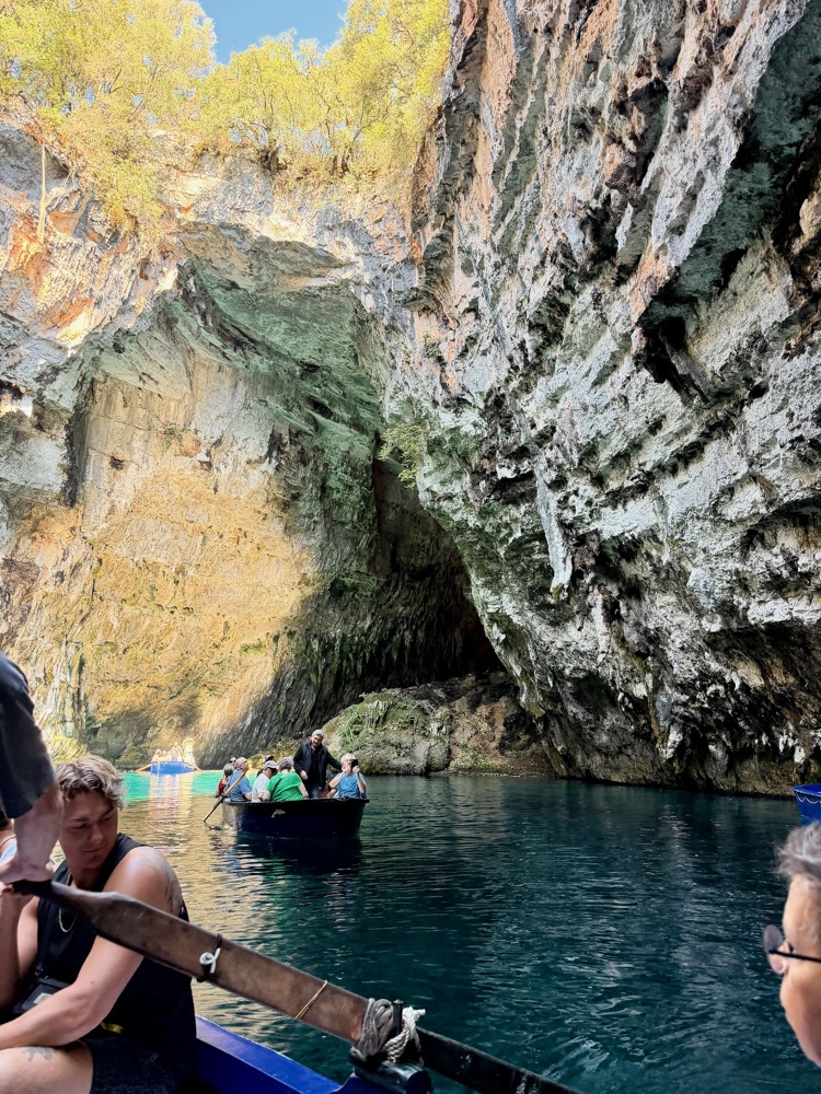 Blick aus einem Ruderboot auf weitere Boote im dunklen Wasser der Höhle