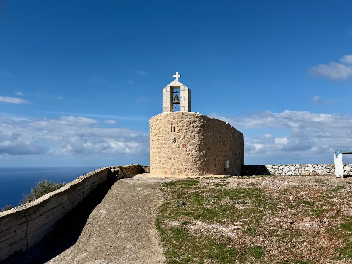 Eine kleine runde Kapelle aus Stein mit Glockengiebel auf einem Felsvorsprung über dem Meer